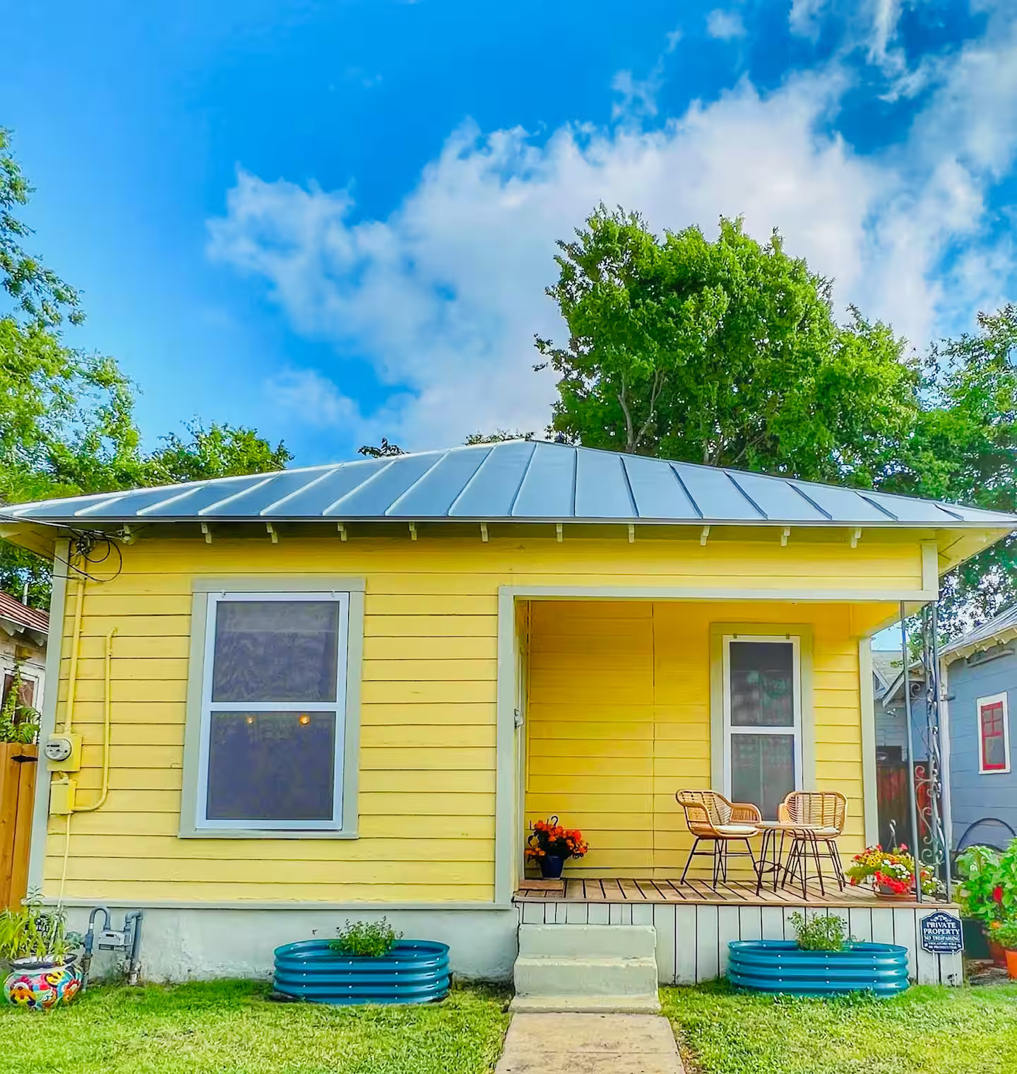 Your yellow East Crockett bungalow, with a welcoming front porch and turquoise planters.